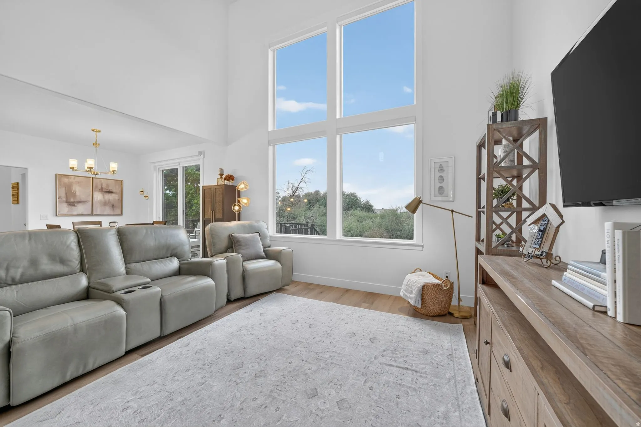 Vaulted ceiling, expansive window array, wood-finish flooring, recessed lighting, and a sliding glass door