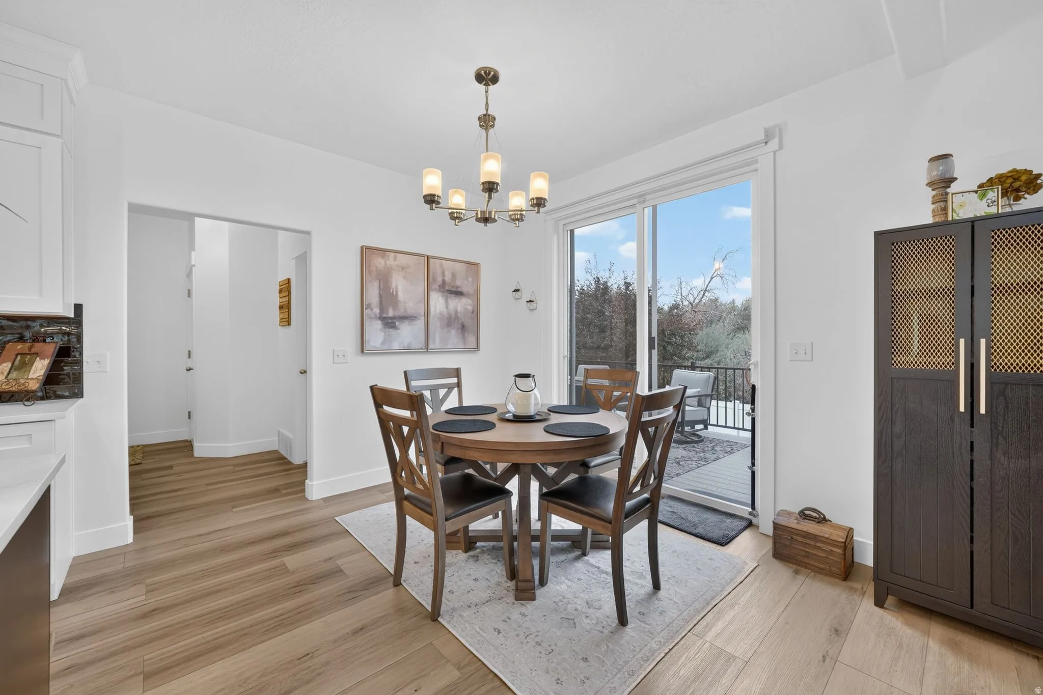 Wood-finish flooring throughout, white walls, and a multi-light chandelier