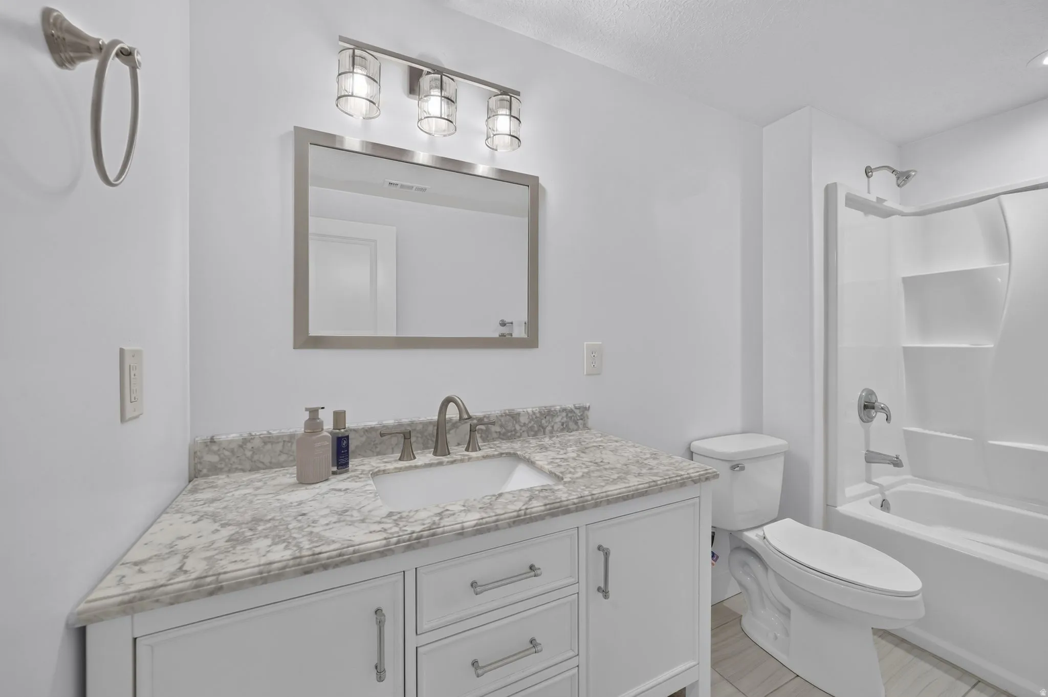 White vanity with brushed nickel hardware, integrated sink, and stone-finish countertop