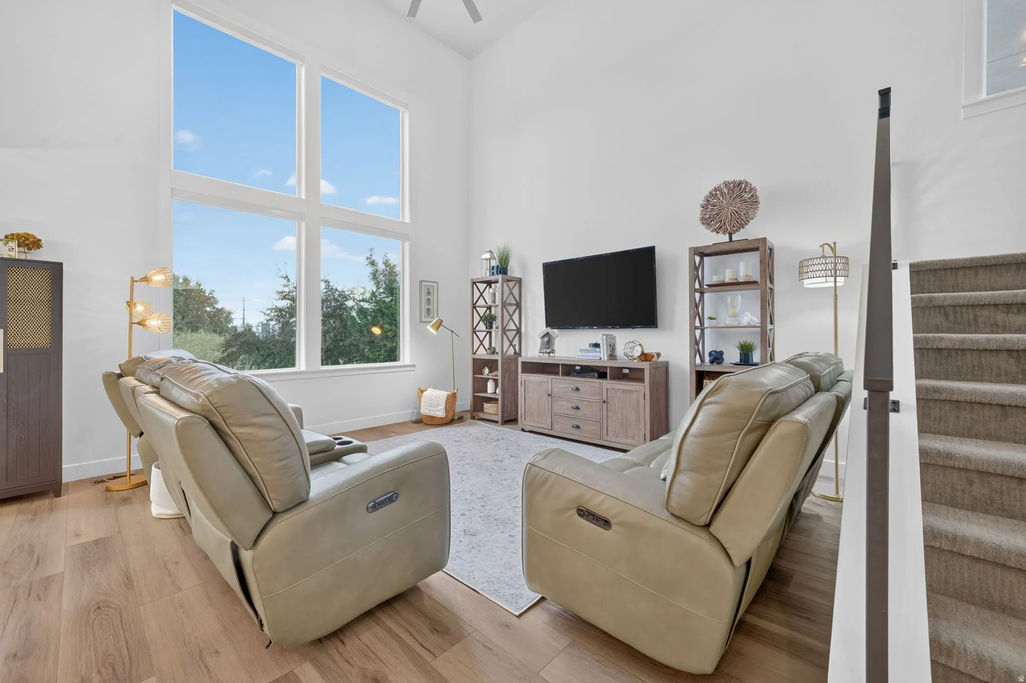 Vaulted ceiling, floor-to-ceiling windows, wood-finish flooring, carpeted staircase, light-toned walls