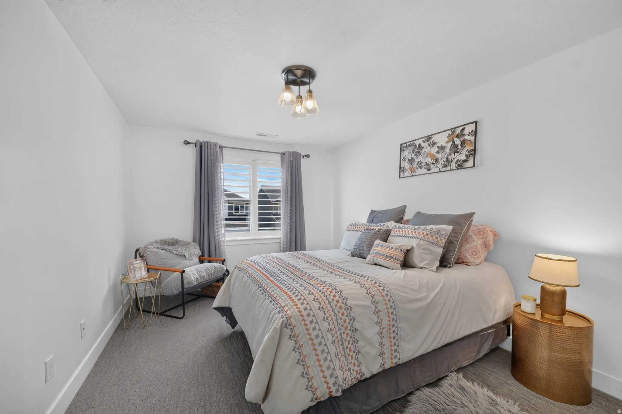 Neutral interior walls, ceiling-mounted light fixture, window with plantation shutters, window with curtains, and gray carpeting