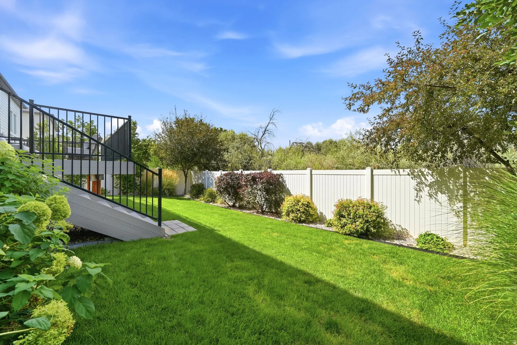Expansive lawn area with a multi-level deck featuring black metal railings