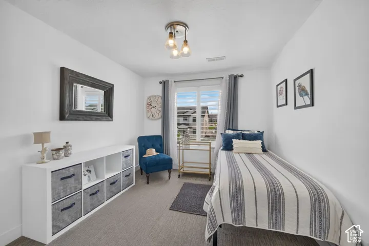 Recessed window with white blinds, overhead multi-bulb light fixture, wall-mounted mirror with a distressed wood frame, and wall-to-wall carpeting