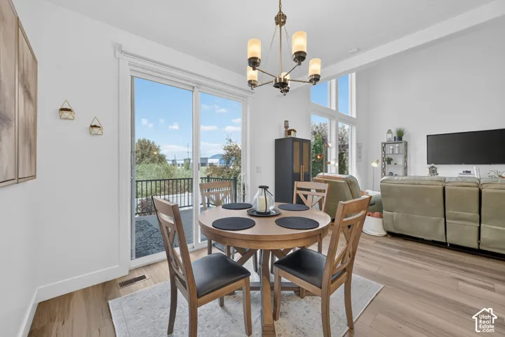 Open-concept living space with wood-finish flooring, a contemporary chandelier, and high ceilings