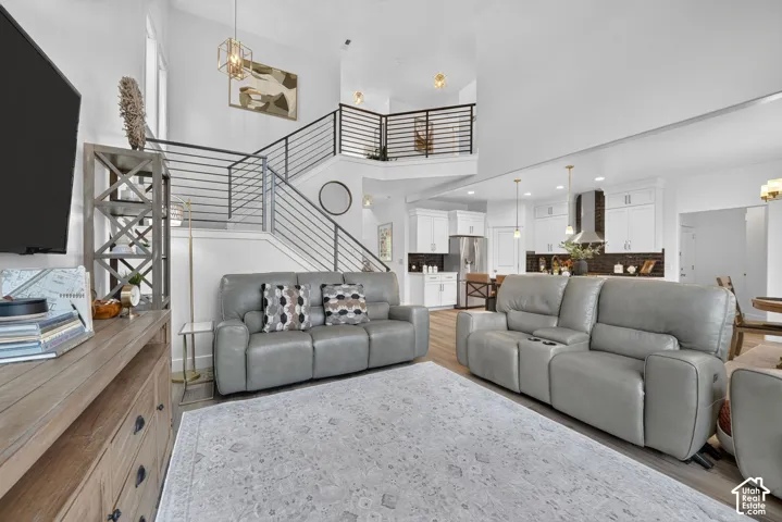 Open-concept living area featuring a two-story ceiling, modern staircase with horizontal railings, and recessed lighting