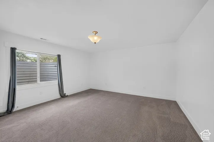 Recessed window with corrugated metal well, neutral carpeting, and a semi-flush mount ceiling light