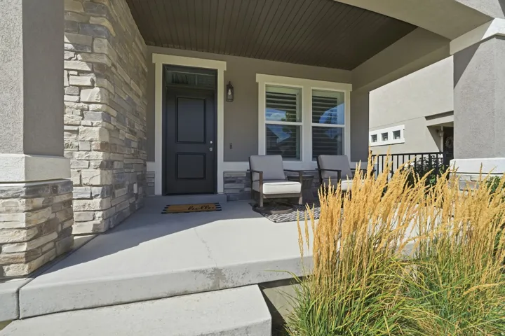 Covered porch featuring a paneled entry door, stone veneer accents, and stucco siding