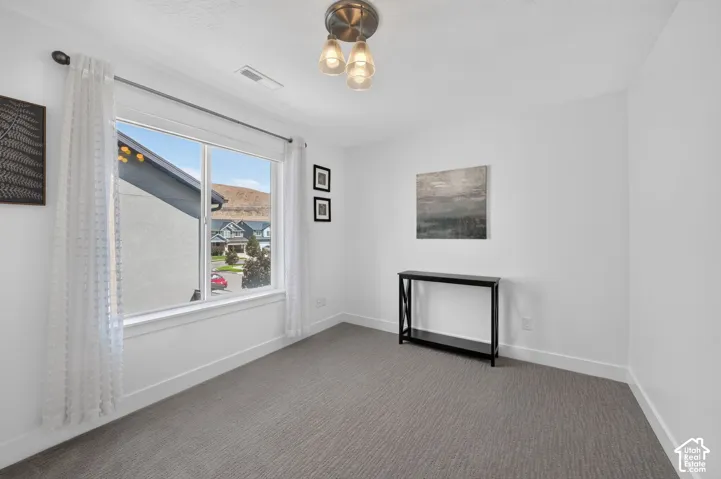 Recessed lighting, large window, neutral wall paint, gray patterned carpeting, and a contemporary ceiling fixture