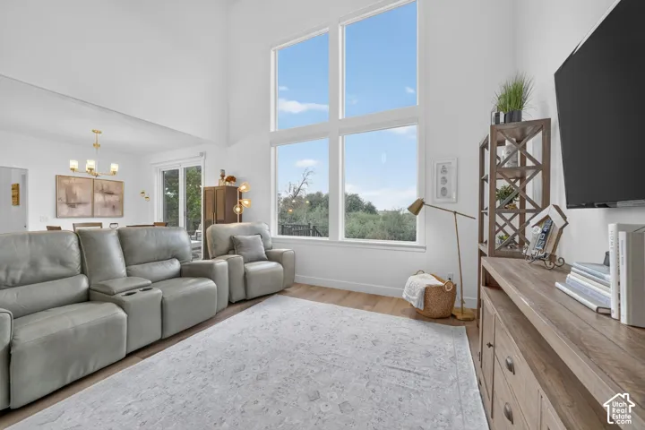 Vaulted ceiling, expansive window array, wood-finish flooring, recessed lighting, and a sliding glass door