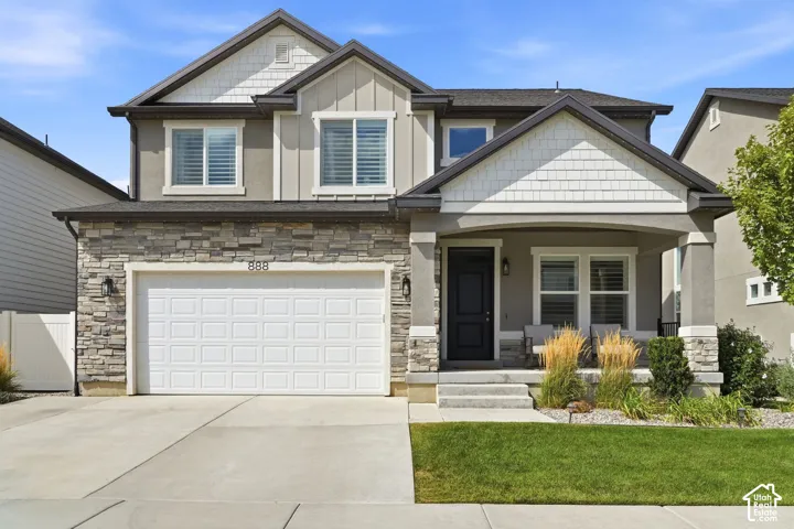 Two-story exterior with stone veneer accents, an attached two-car garage, covered porch, and mature front landscaping
