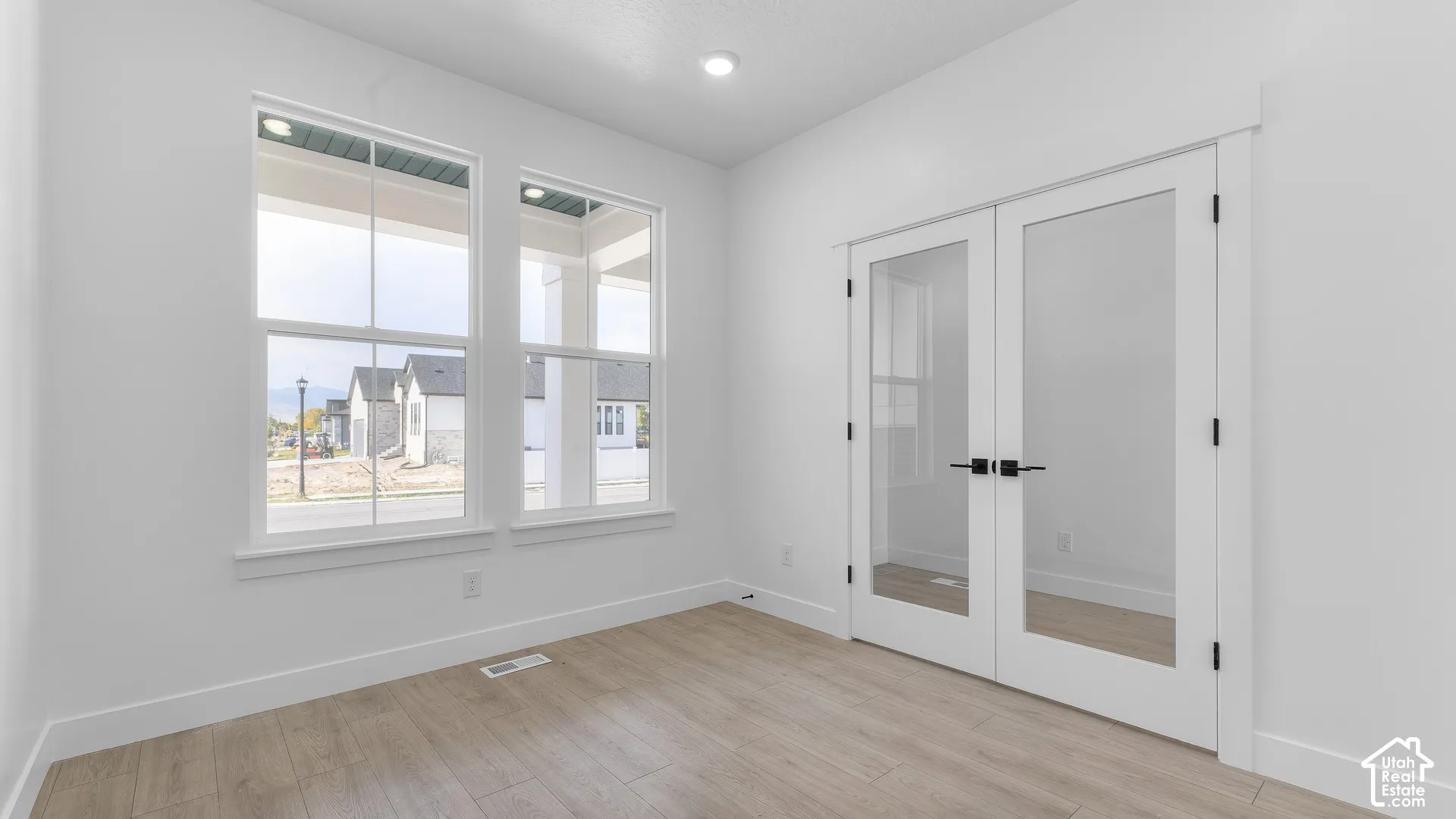 Dual windows, recessed lighting, wood-finish flooring, and double glass-paneled doors with matte black hardware