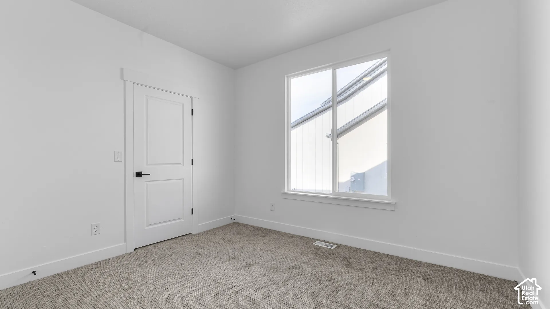 Crisp white walls, neutral carpet, and a two-panel interior door with matte black hardware