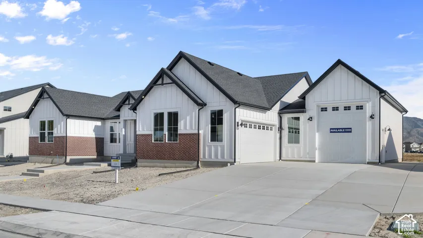 Modern farmhouse exterior with white board and batten siding, dark shingle roof, brick accents, and a concrete driveway