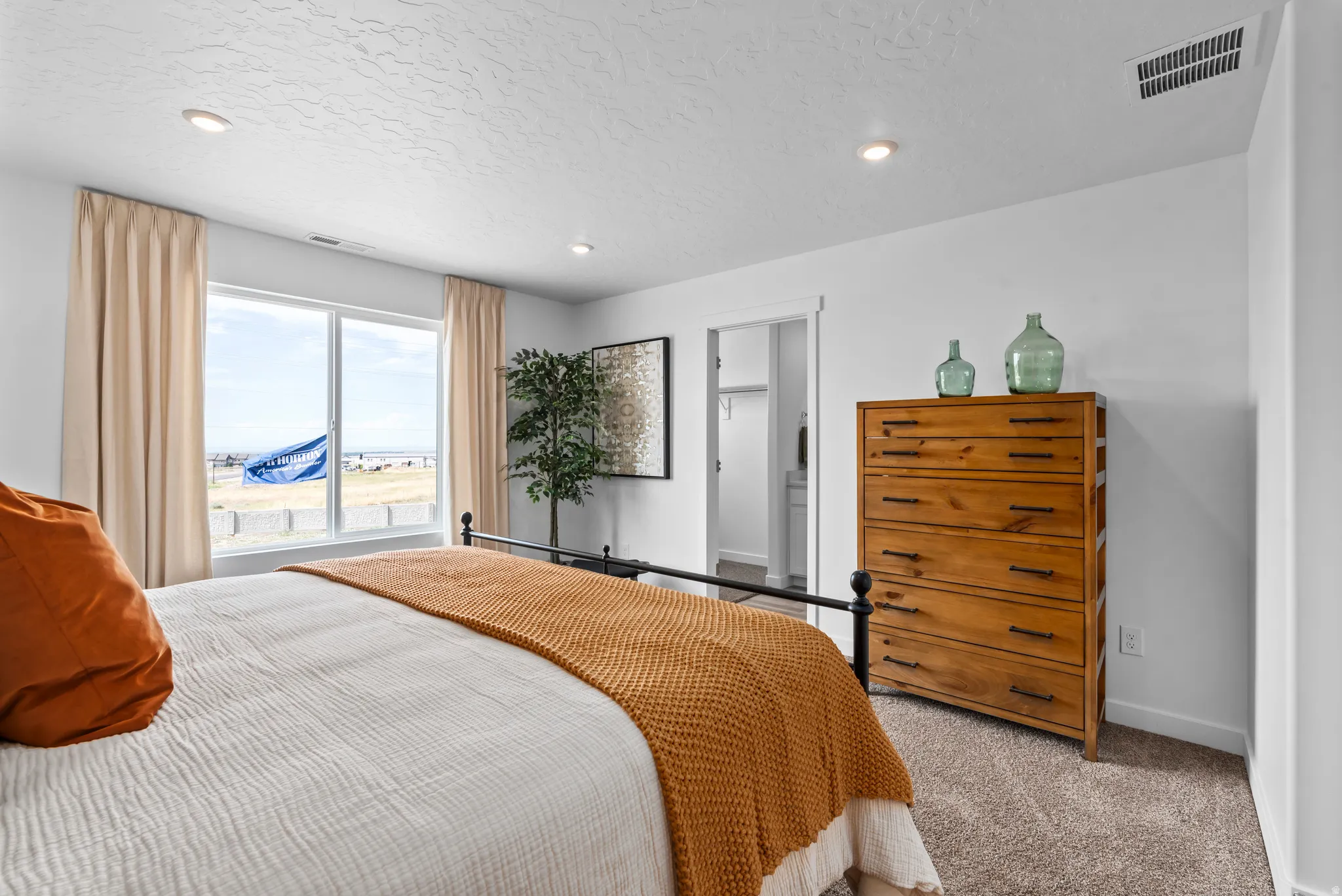 Recessed ceiling lighting, large window with expansive outdoor scenery, carpeted flooring, and a sliding door closet entry