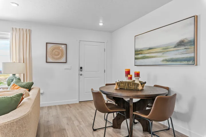 Recessed lighting, light wood-finish flooring, white walls, and a solid white door with black hardware