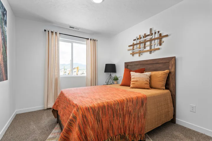 Carpeted bedroom featuring a window with substantial natural light and a built-in wood-finish headboard