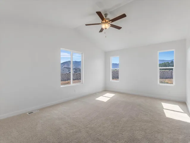Vaulted ceiling, ceiling fan, white walls, carpeted flooring, multiple windows