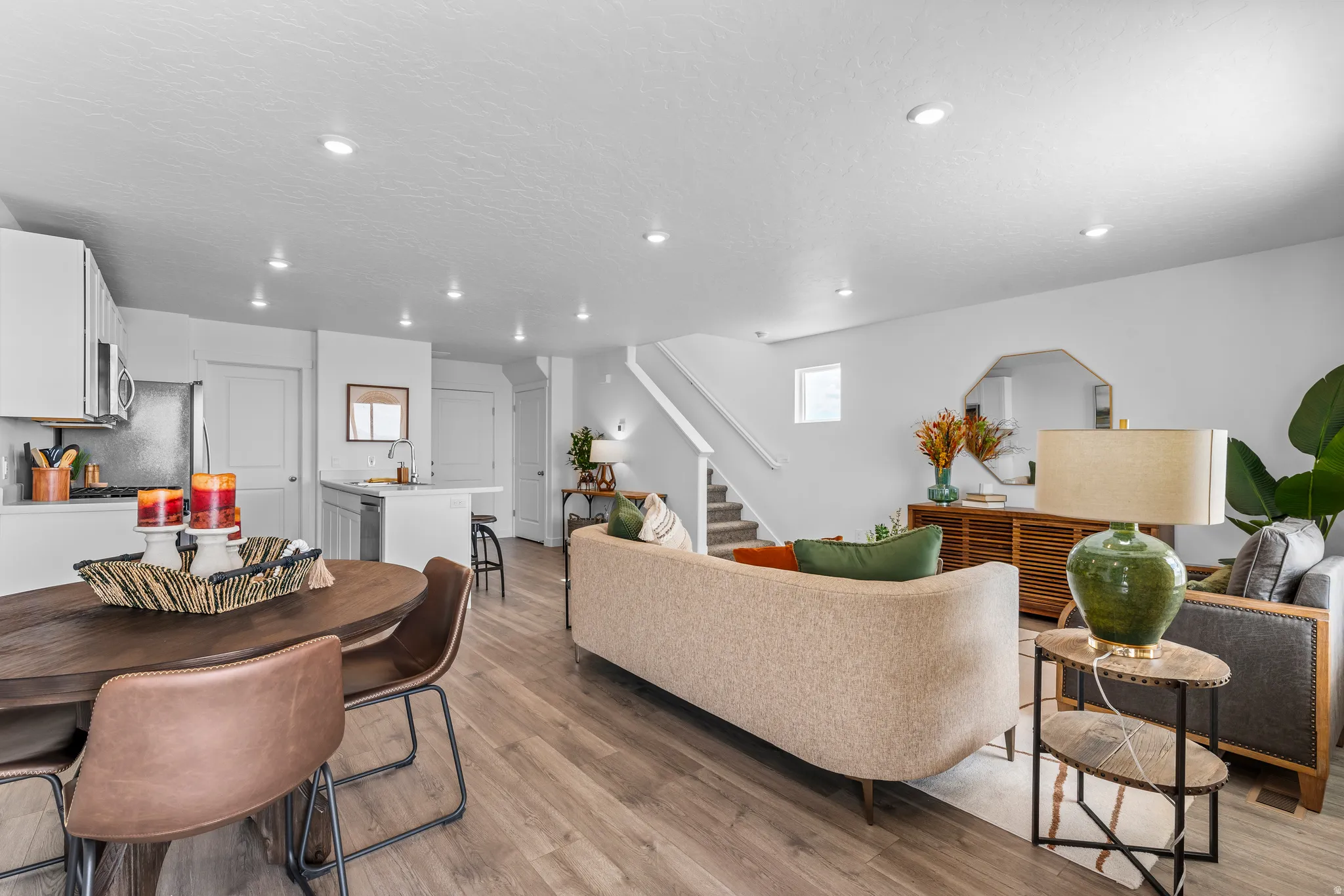 Open concept living area featuring wood-finish flooring, recessed lighting, and a modern kitchen with stainless steel appliances and white cabinetry