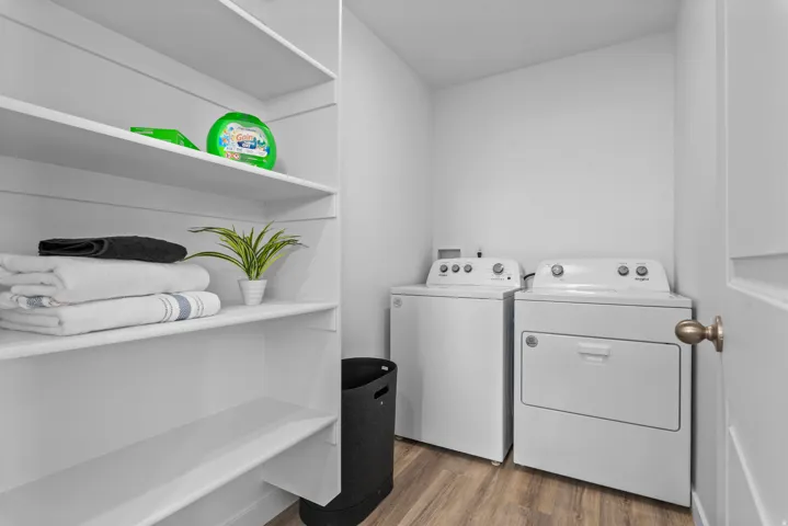 Laundry area featuring built-in shelving, wood-finish flooring, and a white washer and dryer set