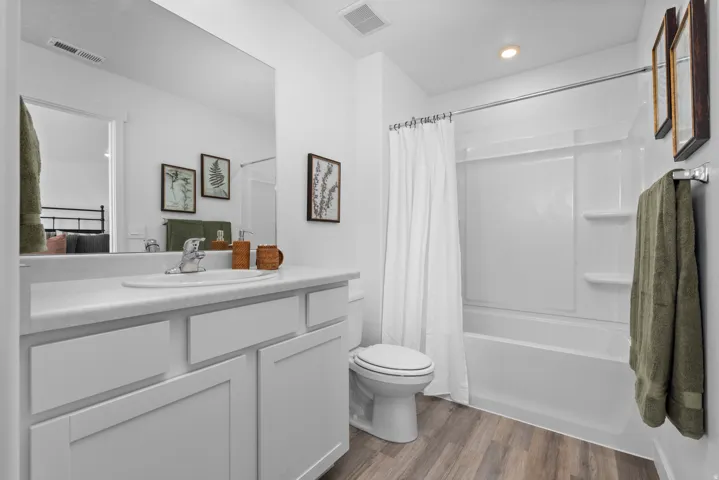 White vanity with a single basin sink, chrome faucet, and expansive wall mirror