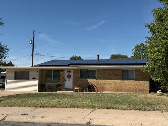 Brick exterior with solar panels and a manicured lawn