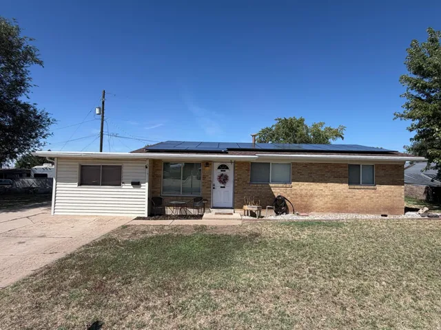 Brick exterior with solar panels, white siding, and a concrete driveway