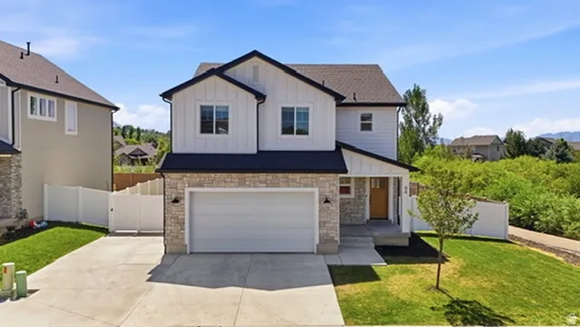 Contemporary two-story residence featuring a two-car garage, stone and siding exterior, front yard landscaping, and a concrete driveway