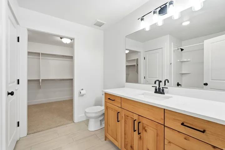 Light wood-finish vanity with white countertop, dual sinks, and matte black fixtures