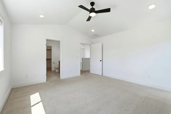 Vaulted ceiling with recessed lighting and a ceiling fan, plush carpet, and white trim
