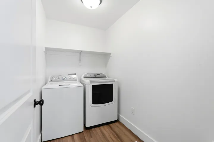 Dedicated laundry space featuring wood-finish flooring and an integrated shelf