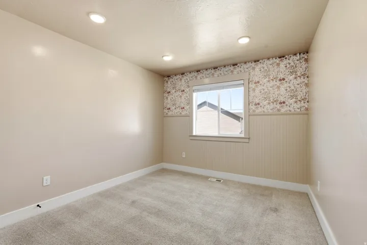Neutral-toned walls with recessed lighting, carpet flooring, a single window, and decorative wainscoting with patterned wallpaper