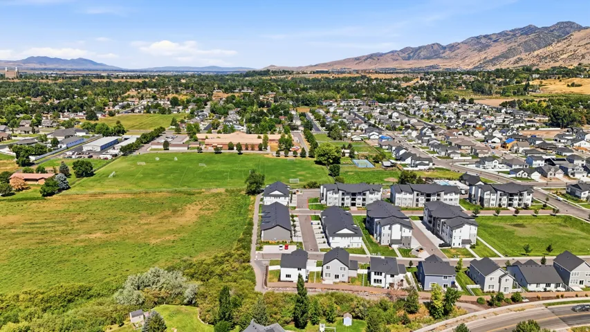 Expansive residential area featuring a mix of single-family homes and multi-unit buildings, surrounded by green spaces and distant mountains