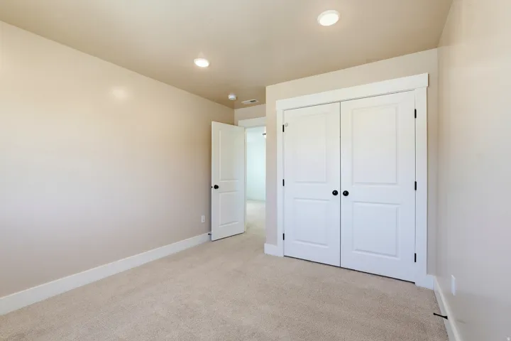 Plush carpet flooring, recessed lighting, white trim, and bi-fold closet doors with black hardware