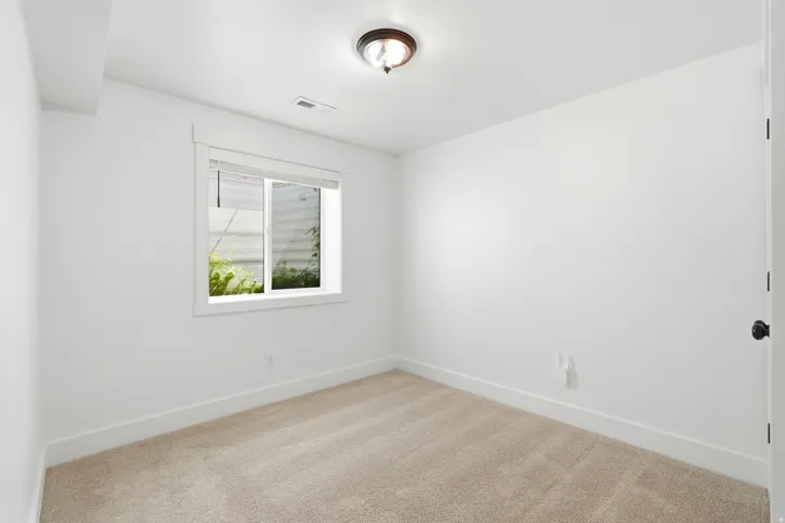 Neutral-toned carpet flooring, white painted walls, and a single window with blinds