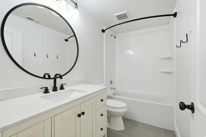 White vanity with a quartz countertop, integrated sink, and black fixtures