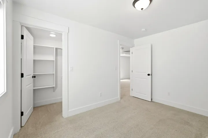 Plush carpet flooring, white walls, built-in closet shelving, recessed lighting, and a semi-flush mount ceiling fixture