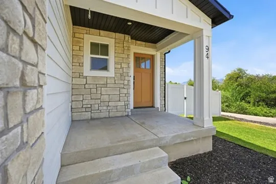 Stone and siding exterior with a covered porch, featuring a wooden entry door with glass panels