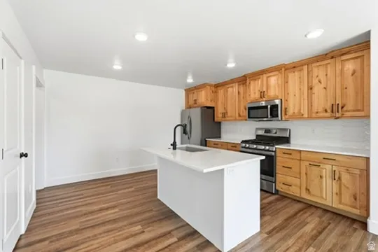 Wood-finish flooring, recessed lighting, and white walls throughout