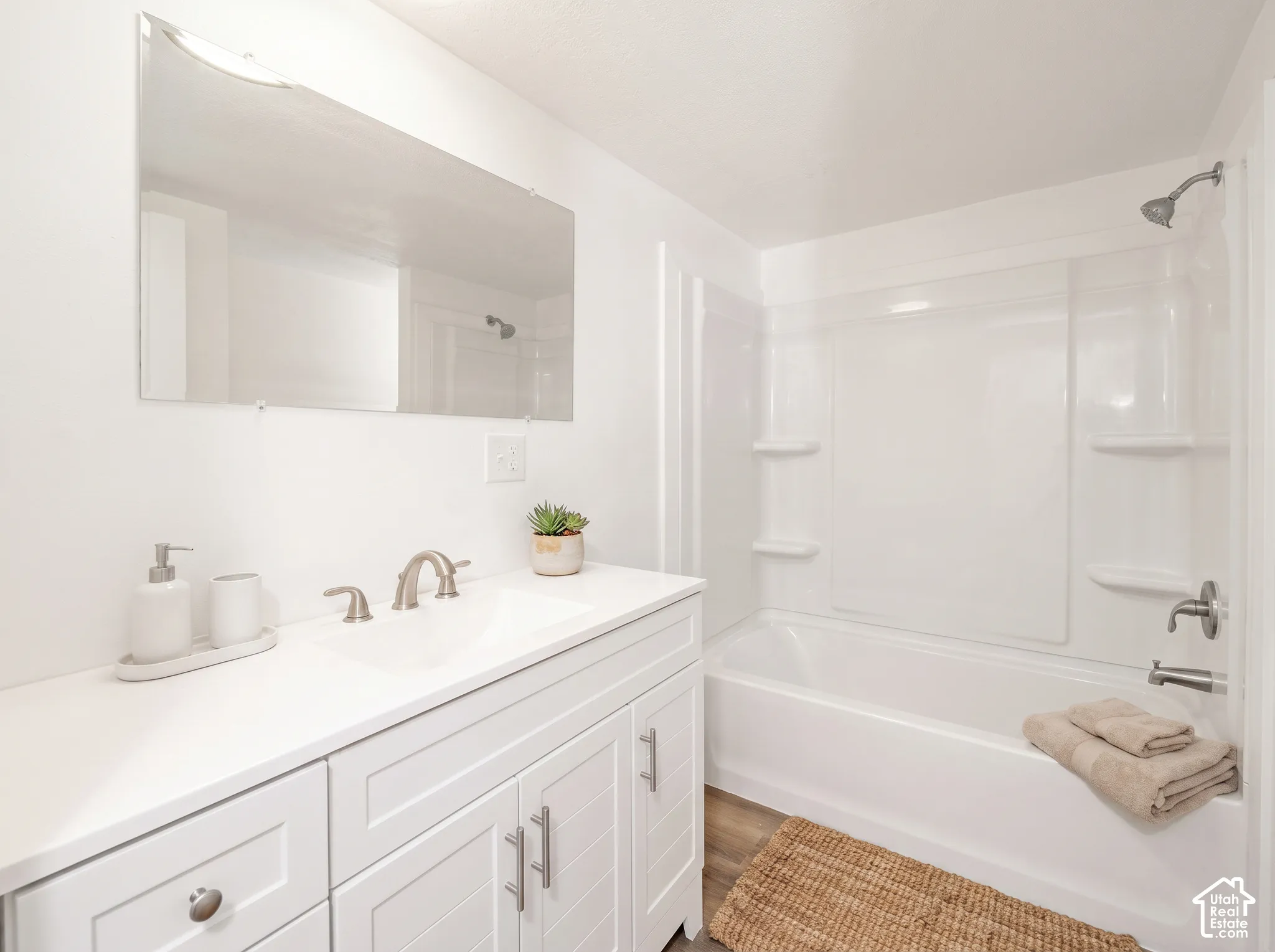 White vanity with integrated sink, brushed nickel faucet, and wood-finish flooring