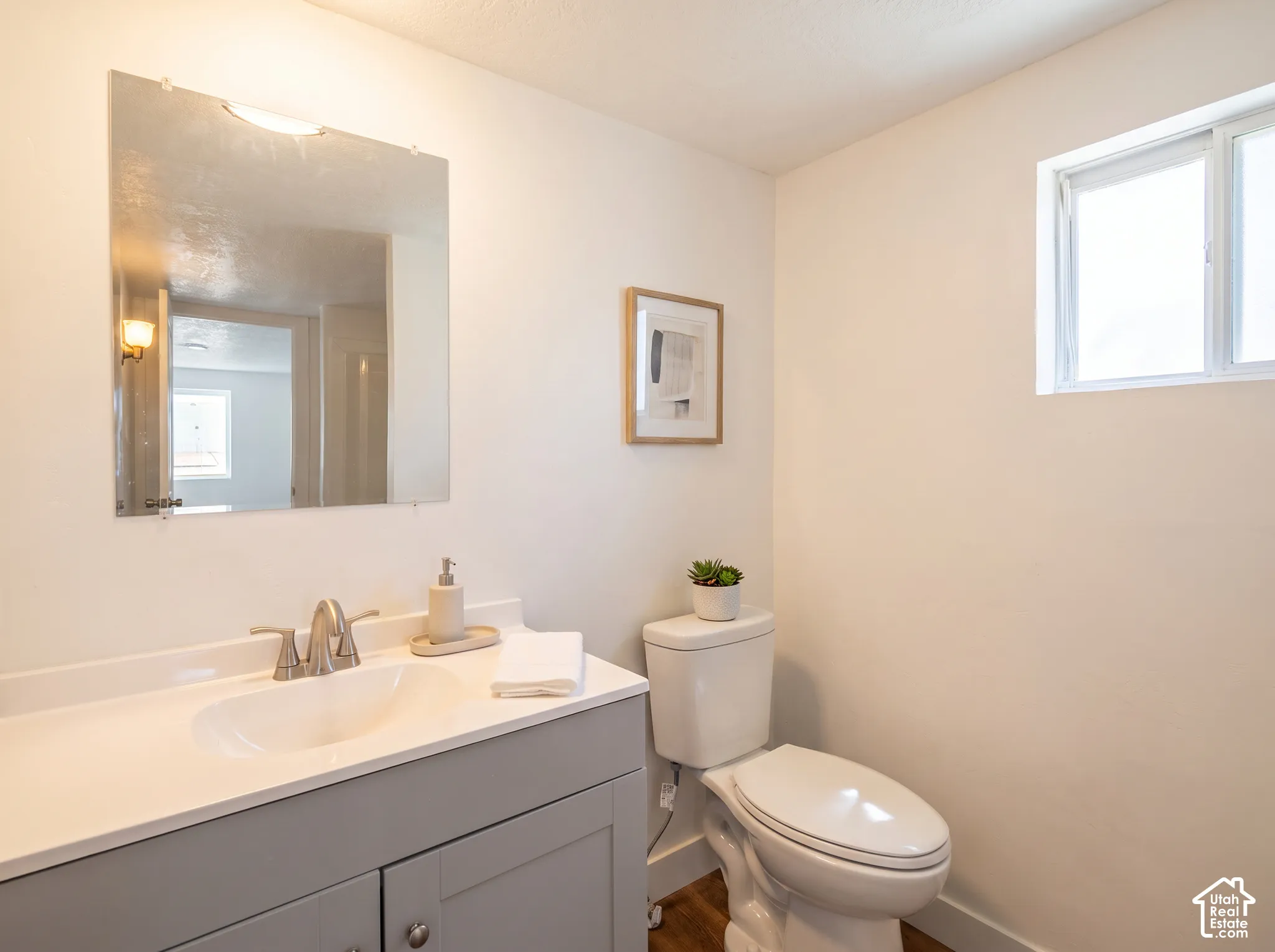 Vanity with an integrated sink, brushed nickel faucet, large wall mirror, and toilet