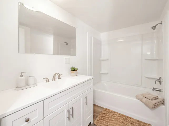 White vanity with integrated sink, brushed nickel faucet, and wood-finish flooring
