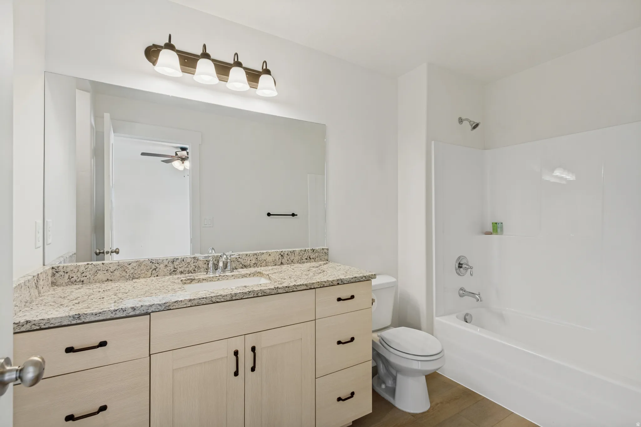Double vanity with a light-toned countertop, integrated sink, and light wood-finish cabinetry