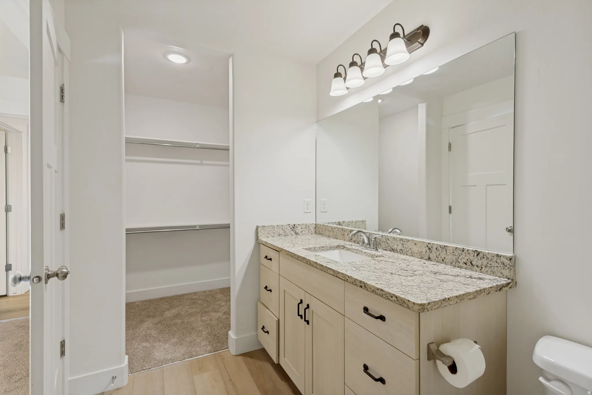 Integrated vanity with a stone countertop, under-mount sink, and dual-tone cabinetry