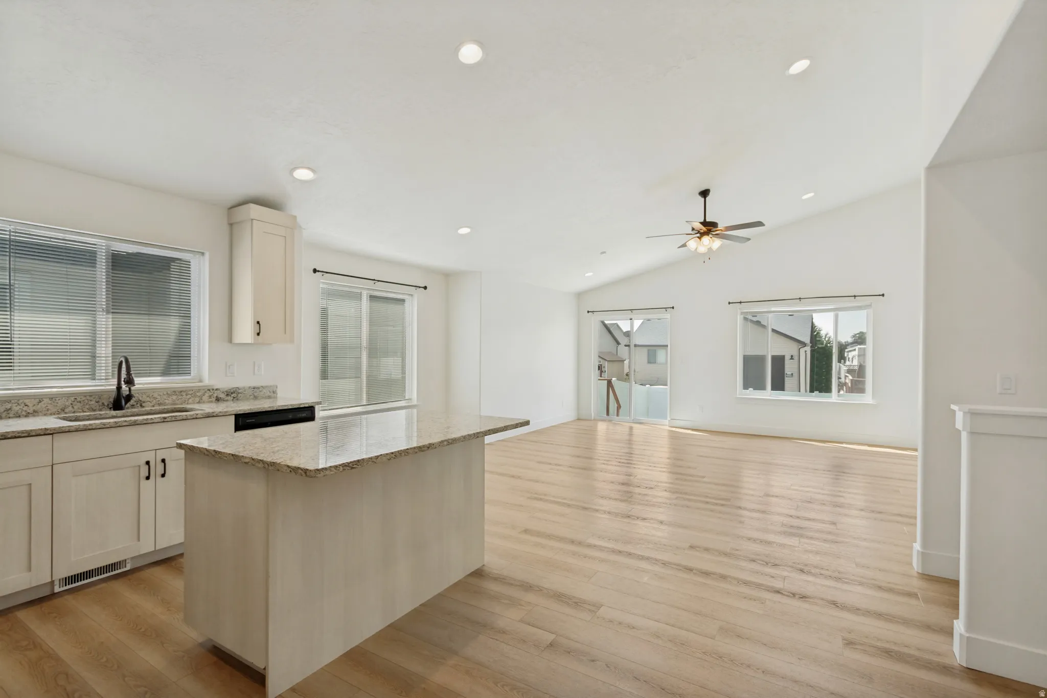 Kitchen island with light-toned countertop, recessed lighting, wood-finish flooring, vaulted ceiling, and ceiling fan