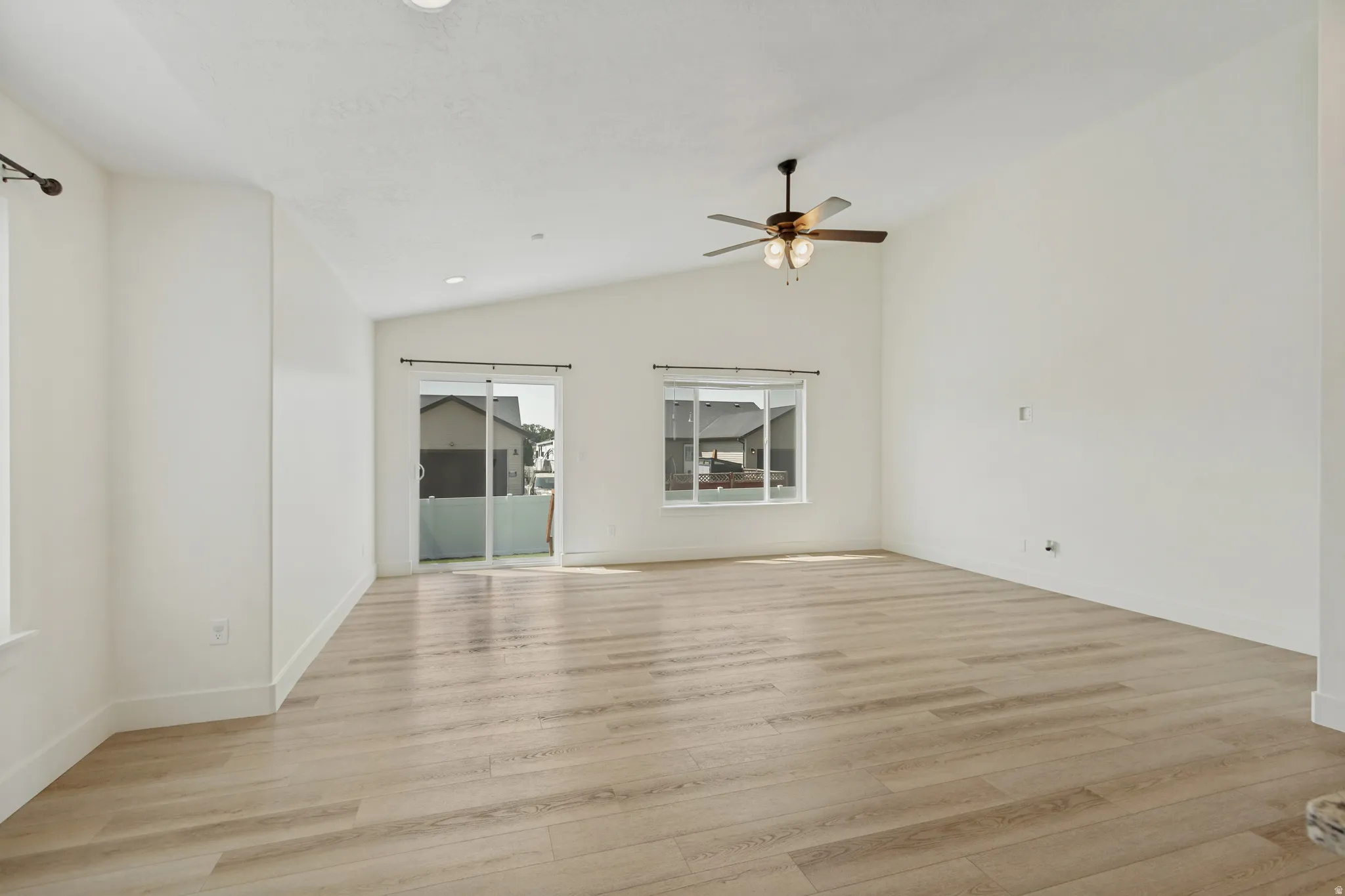 Vaulted ceilings, wood-finish flooring, sliding glass door, recessed lighting, and a ceiling fan