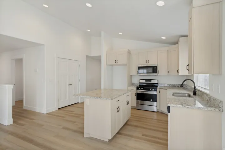 Kitchen featuring light wood-finish flooring, recessed lighting, light-toned cabinetry, stainless steel appliances, and granite countertops