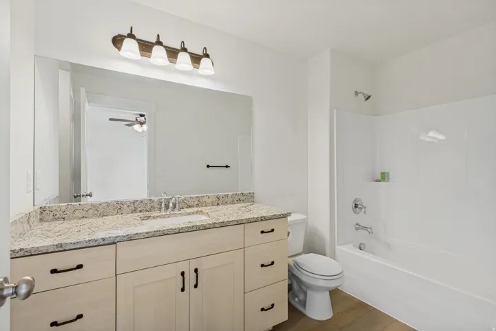 Double vanity with a light-toned countertop, integrated sink, and light wood-finish cabinetry