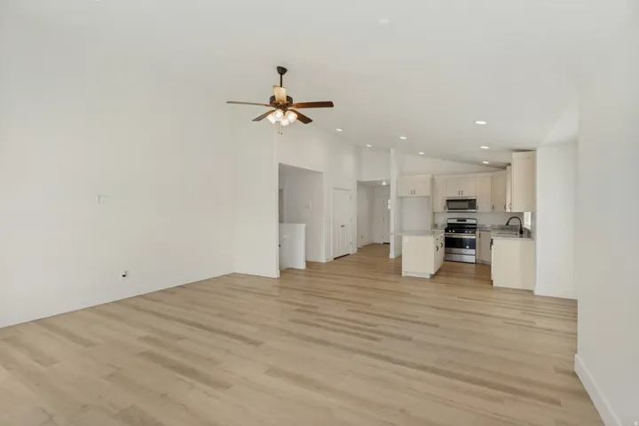 Vaulted ceilings, wood-finish flooring, ceiling fan, recessed lighting, and kitchen island with built-in sink