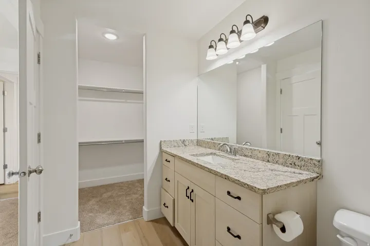 Integrated vanity with a stone countertop, under-mount sink, and dual-tone cabinetry