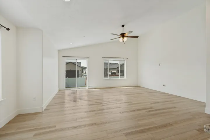Vaulted ceilings, wood-finish flooring, sliding glass door, recessed lighting, and a ceiling fan